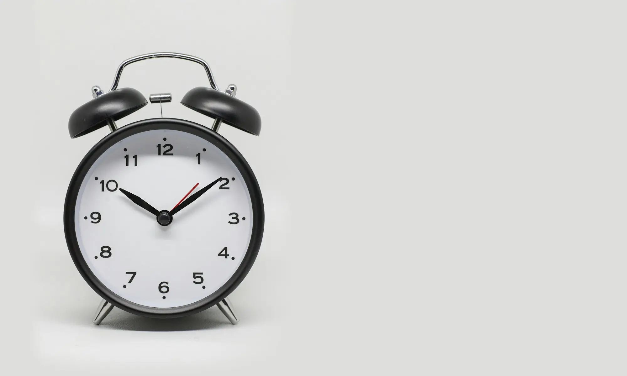 Black and white alarm clock on a plain white background, a deadline approaching