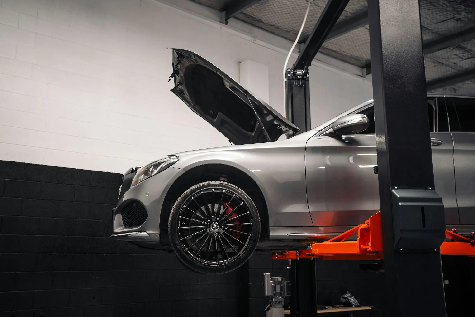 Car raised on a hydraulic hoist in a mechanic's workshop, ready for urgent repair