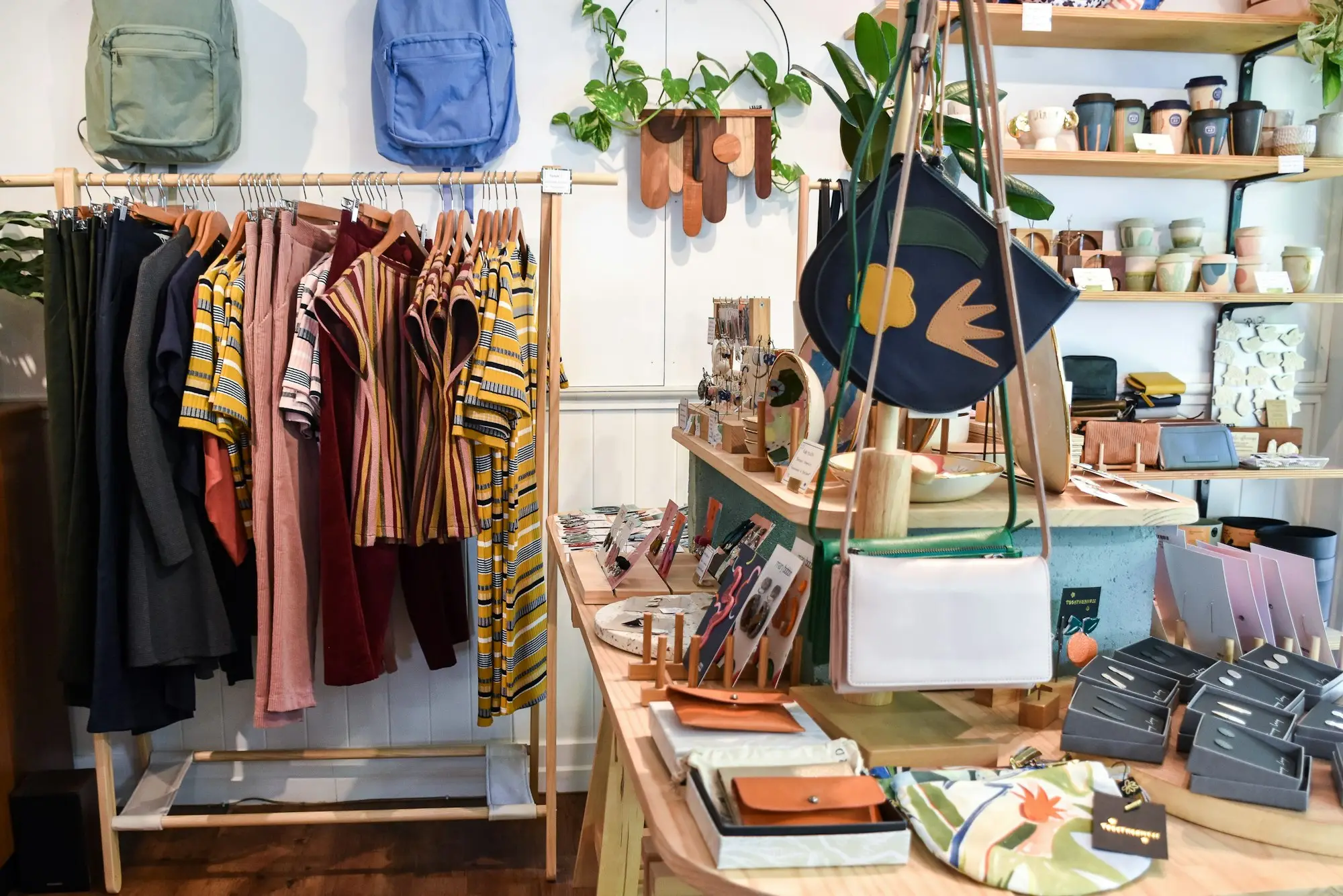Clothes on a rack beside a wooden table in a small boutique