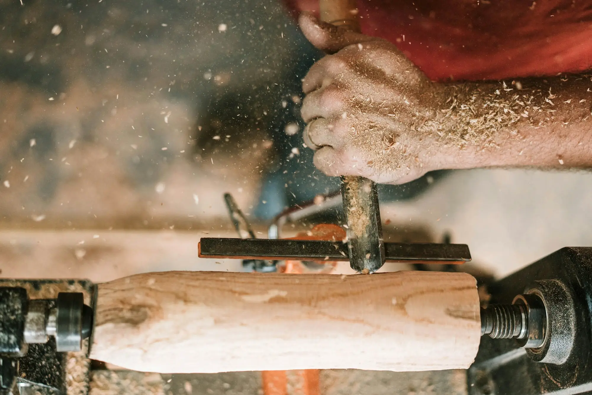 Hand holding a grey metal tool in a workshop