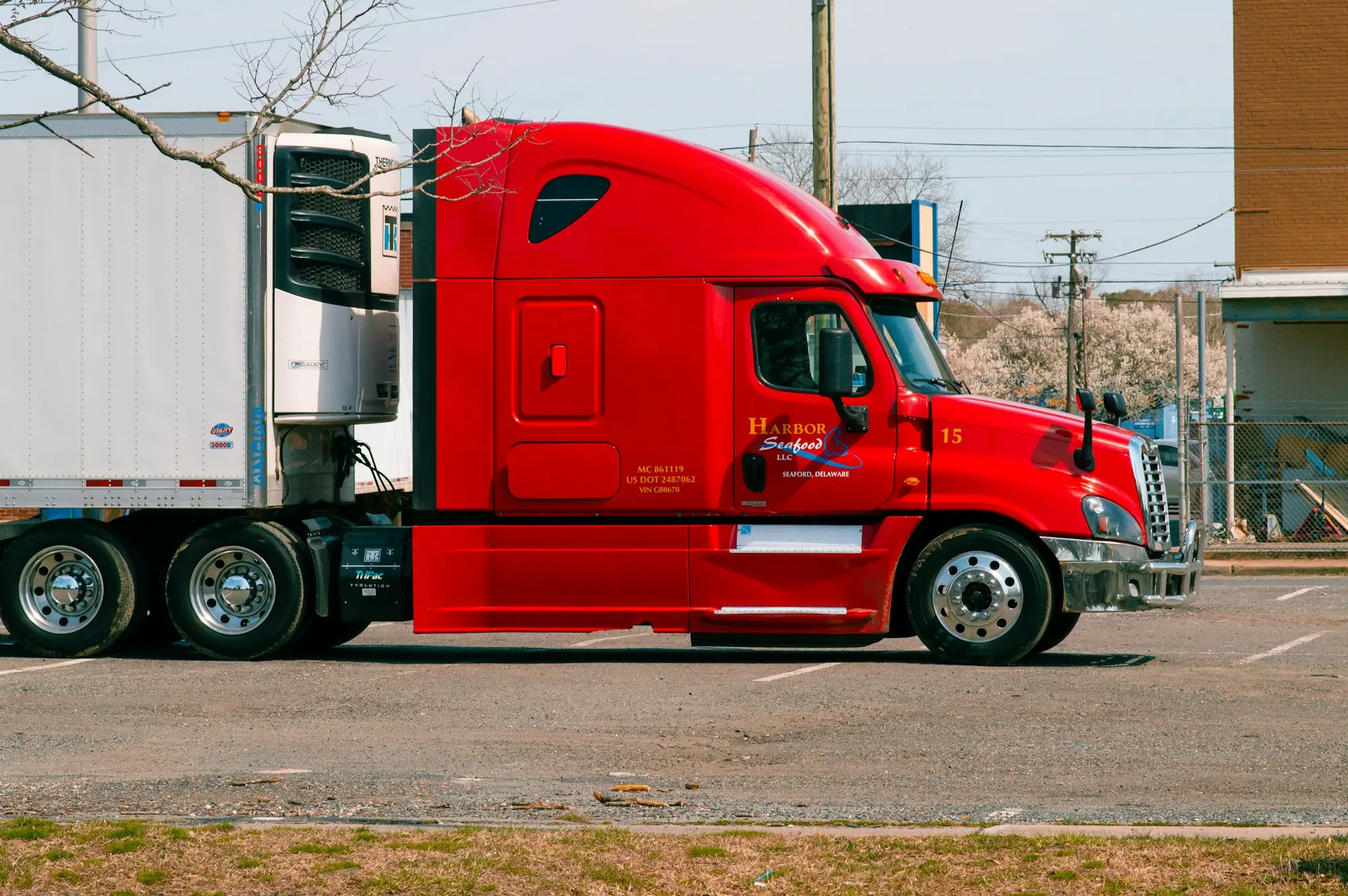 Red and white freight truck driving along a highway in daylight